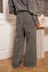 Pantalón de denim celeste con corte amplio y cintura elastizada. Presenta detalles de pedrería en los laterales.