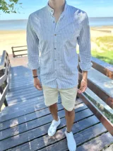 Camisa de manga larga con cuello mao, a rayas verticales en tonos gris y blanco, con botones frontales de madera.