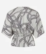 Blusa de tela satinada color gris con estampado abstracto en negro y blanco, escote en V cruzado, mangas cortas y cintura elastizada.