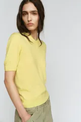 Jersey de punto liso color amarillo, confeccionado en lana 100%, con cuello pico y manga corta.