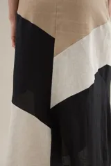 Falda larga de lino con diseño de cortes diagonales en bloques de color blanco, beige y tostado, de corte evasé y caída fluida.