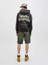 Canguro negro con capucha, de corte holgado y mangas raglán. Presenta un gran estampado en color beige en la espalda con la inscripción "Studio Originals" y texto descriptivo, además de puños y dobladillo acanalados.