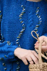 Buzo de lana merino tejido a mano, color azul vibrante, con diseño de ochos tradicionales intervenidos con hilos en contraste que recorren la prenda. Presenta cuello redondo y corte a la cintura.