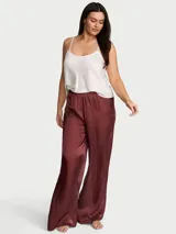Pantalón de pijama de satén semitransparente color bordó, de talle medio con cintura elástica y silueta de pierna ancha.