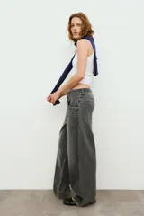 Jeans de tiro medio con cinco bolsillos, cintura doble a contraste y detalles de rotos. Cierre frontal con cremallera y botones metálicos.