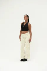 Top negro tipo halter, ajustado al cuerpo, con escote drapeado y detalles de ojales metálicos plateados a lo largo del borde del escote.