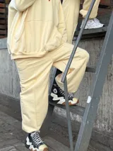 Pantalón deportivo de tiro alto, color amarillo, con bolsillos laterales y puños elásticos en los tobillos.