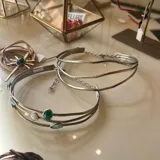 Gargantilla rígida de diseño triple con estructura ondulada en metal dorado, que se completa con una cadena fina ajustable en la parte posterior.