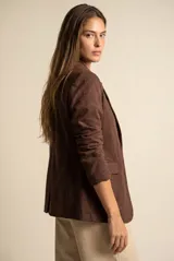 Blazer de gamuza sintética color marrón, con solapas clásicas, cierre frontal de dos botones y bolsillos laterales con solapa.