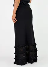 Pollera larga de punto color negro, con diseño ajustado en la parte superior y detalles de volados con textura en el ruedo.