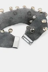 Gargantilla tipo choker de malla metálica color gris plomo, con apliques de cristales facetados colgantes. Cierre con clip metálico.
