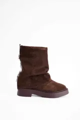 Bota de caña media confeccionada en cuero vacuno color marrón oscuro, con diseño de pliegues en la caña y suela de goma al tono con textura estriada.