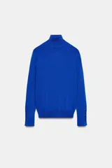 Jersey de cuello alto y manga larga, confeccionado en punto liso, con detalle de botones en los puños.