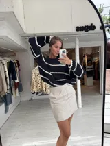 Buzo de tejido de punto grueso en color gris con rayas horizontales en color crema, de corte holgado, cuello redondo y mangas largas.