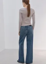 Jeans de denim azul de corte wide leg, con aplicación de pequeños tachas o strass plateados en toda la prenda.