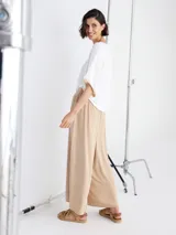 Pantalón palazzo color blanco con cintura alta y dos botones decorativos.