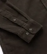 Camisa de hombre color verde oscuro, confeccionada en terciopelo, con cuello clásico, manga larga y dos bolsillos frontales con solapa y botón. Cierre frontal con botones.