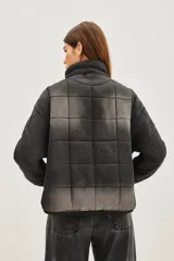 Campera acolchada de corte holgado con diseño de costuras cuadradas, cierre frontal con cremallera y cuello alto. Presenta un acabado lavado en tonos gris y negro.