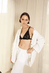 Sostén tipo bralette negro de encaje elastizado, con diseño triangular y breteles con detalle de encaje.