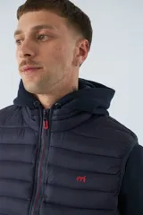 Chaleco puffer verde oliva con cierre frontal y bolsillos laterales con cierre. Interior forrado en color naranja.