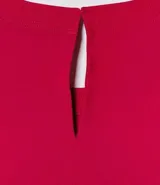 Blusa blanca de poliéster con cuello redondo, mangas cortas, cierre trasero en forma de gota, pequeñas aberturas laterales y acabados en pespuntes en las mangas y el cuello.