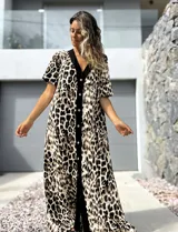 Vestido largo de corte holgado con estampado animal print de leopardo. Presenta una botonadura frontal completa sobre una franja vertical de color negro que recorre el centro de la prenda, cuello en V y mangas cortas.