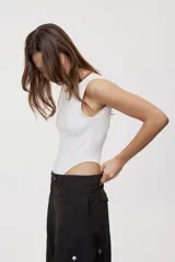 Body de silueta ajustada de color blanco, sin mangas, con escote redondo amplio y diseño de corte alto en las piernas.