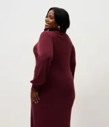 Vestido midi de punto acanalado color bordó, con cuello redondo y mangas largas abullonadas. Presenta un corte recto y fluido, confeccionado en una mezcla de viscosa y poliamida.
