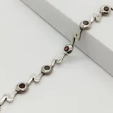 Pulsera de eslabones de plata 925 con diseño ondulado, intercalados con engastes circulares que contienen piedras de granate.