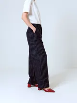 Pantalón de vestir negro con finas rayas verticales blancas, corte recto y tiro alto.