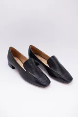 Mocasines bajos de cuero negro con textura croco y suela plana.