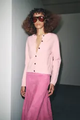 Chaqueta de tejido de punto color verde musgo, de corte cropped, con cuello redondo y cierre frontal de botones oscuros.