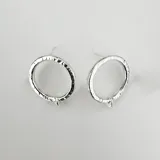 Par de caravanas plateadas con forma de círculo y textura martillada.