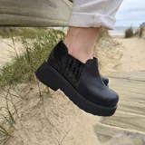 Zapatos tipo botineta de cuero color negro, con plataforma gruesa y elásticos laterales con textura.
