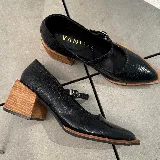 Zapato tipo Mary Jane de cuero vacuno con textura grabada, color marrón oscuro. Presenta una puntera cuadrada, taco bloque de madera y una tira con hebilla metálica sobre el empeine.