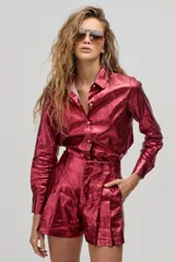 Short de tiro alto color rojo metalizado con pinzas delanteras, bolsillos laterales y cierre frontal con gancho metálico.