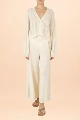 Cardigan de punto color marfil con cuello en V, cierre frontal de botones y mangas largas abullonadas. Presenta un diseño de tejido con textura vertical y corte corto.