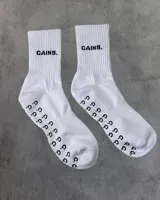 Par de medias deportivas blancas con texto 'GAINS.' en negro y agarre antideslizante con patrón de puntos 'G.G.' en la planta del pie.