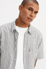 Camisa de manga corta Levi's con diseño de rayas verticales en tonos gris y blanco. Presenta cuello clásico, cierre frontal con botones y un bolsillo en el pecho con la etiqueta roja característica de la marca.