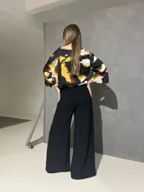 Blusa de manga larga acampanada con estampado abstracto en tonos negro, blanco, verde lima y caramelo, de corte holgado.