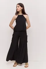 Pantalón negro de tiro alto y calce amplio, con silueta oxford, caída suave y detalle de tiras laterales regulables.