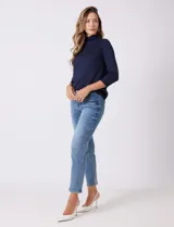 Jean azul de calce semi-ajustado, estilo Mom Slim, de tiro alto, relajado en la cadera y muslos, con pierna que se angosta levemente hacia el tobillo. Tiene pretina clásica con pasadores para cinturón, cierre frontal con cremallera y botón metálico, y bolsillos delanteros y traseros.