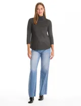 Buzo de tejido fino en color gris oscuro, con cuello alto acanalado y mangas tres cuartos. Presenta un diseño con líneas acanaladas en diagonal desde el cuello hacia las sisas y pequeños tajos laterales en el ruedo.