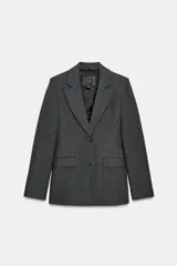 Blazer entallada de color gris oscuro, confeccionada en tejido con algodón. Presenta un cuello solapa con aplicación de pelo sintético desmontable, manga larga, bolsillos delanteros con solapa y cierre frontal con botones.