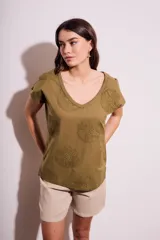 Remera de algodón color blanco con cuello en V y mangas cortas. Presenta un diseño con flores bordadas en relieve y detalles calados en el tejido.