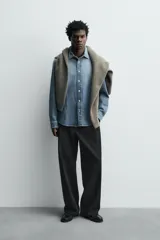 Camisa de corte relajado confeccionada en denim de algodón con efecto lavado. Presenta cuello solapa, cierre frontal de botones y mangas largas con puños abotonados.