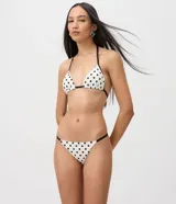 Bombacha de bikini colaless de microfibra, color blanco con estampado de lunares negros y tiras finas laterales en contraste.