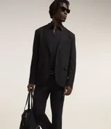 Pantalón de vestir para hombre, color beige claro, de corte slim y sastrería. Presenta cierre frontal con botón y cremallera, y bolsillos laterales y traseros.