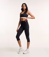 Pantalón corsario deportivo negro, confeccionado en poliamida y elastano, con cintura alta, bolsillos laterales y detalle de línea contrastante en el lateral.