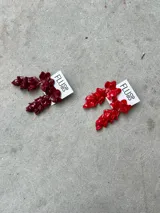 Aros largos hechos a mano en porcelana color borgoña con forma de flores irregulares. El perno es de acero.